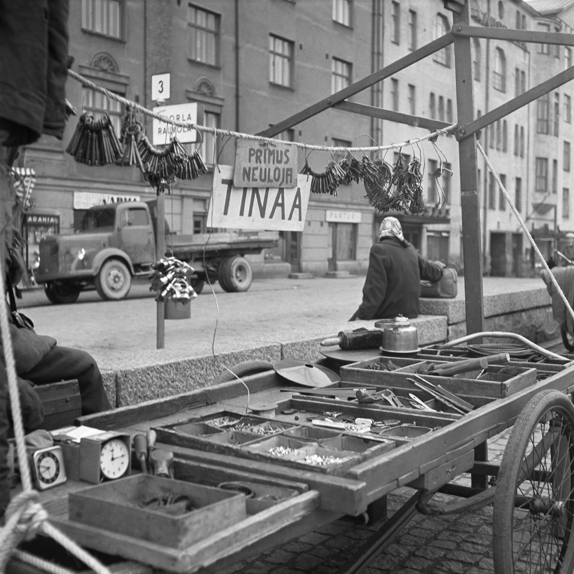 Puutorin myyntikärry, jossa avaimia, työkaluja ja kyltit Tinaa ja Primus-neuloja, vuonna 1955